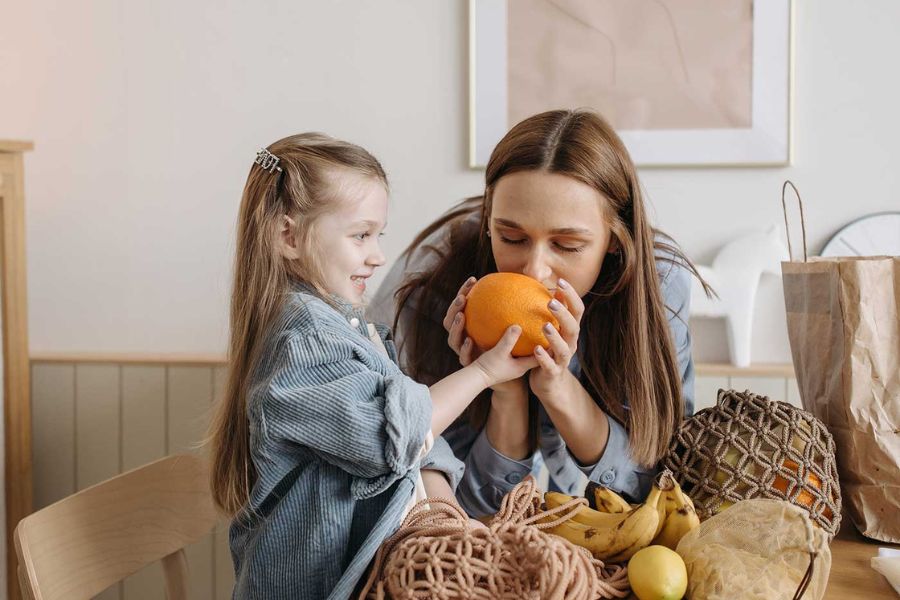 Madre e hija compartiendo frutas en un momento cotidiano, representando la importancia de los límites con amor y presencia en la infancia.