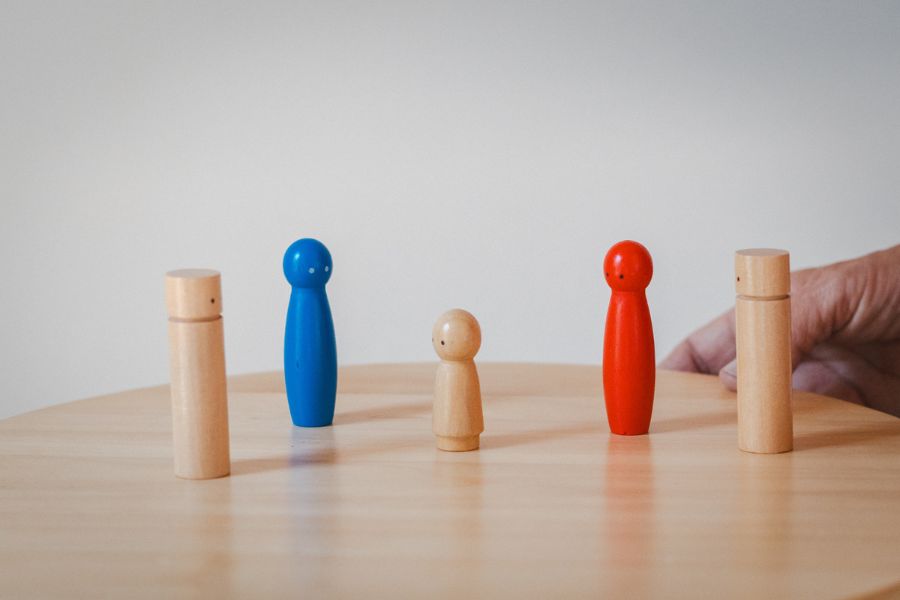 Figuras de madera de distintos tamaños y colores usadas en las Constelaciones Familiares, colocadas sobre una mesa, representando a los miembros del sistema.