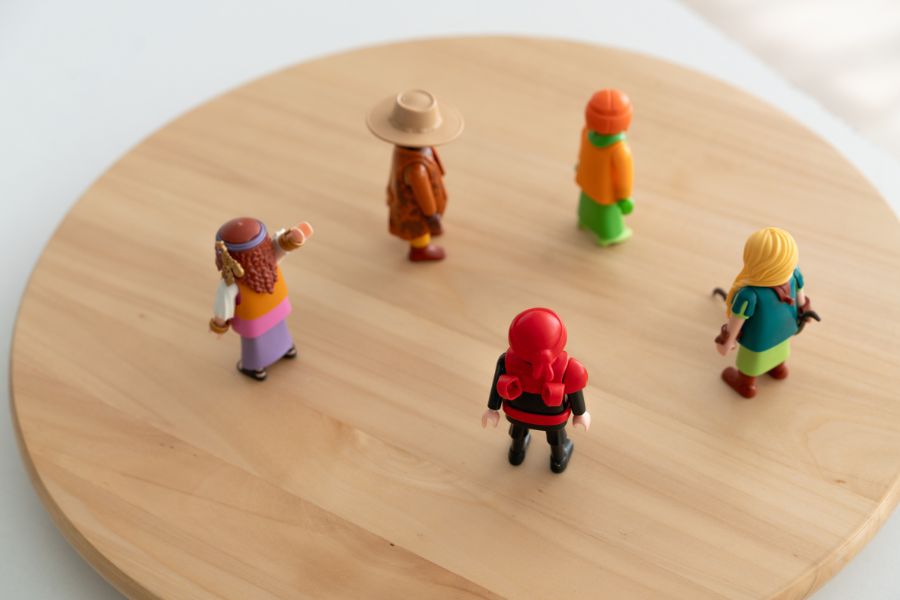 Cinco figuras de playmobil colocadas sobre una tabla de madera redonda, representando las dinámicas de un sistema en el contexto de las Constelaciones Familiares y las terapias complementarias