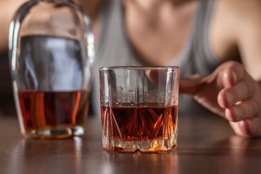 Persona con un vaso de alcohol, representando el consumo como síntoma de un dolor no expresado y dinámicas familiares invisibles.