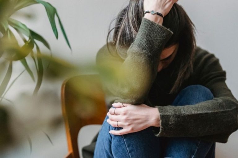 Mujer aislada en posición recogida, representando cómo las adicciones surgen como síntomas de conflictos familiares y emocionales dentro de un sistema relacional complejo.