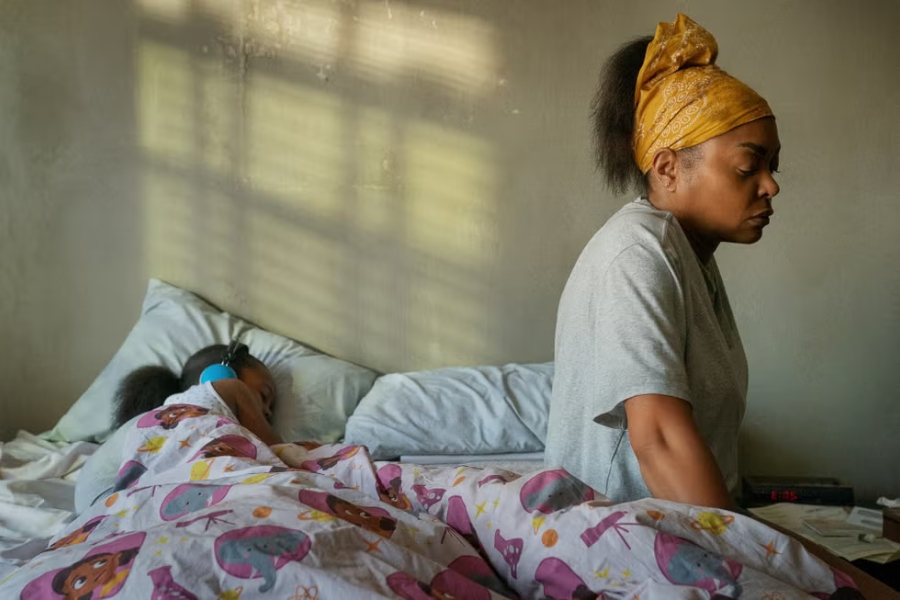 aniyah, visiblemente disociada, yace en la cama mientras su hija duerme a su lado, reflejando la fragilidad y el impacto del trauma.