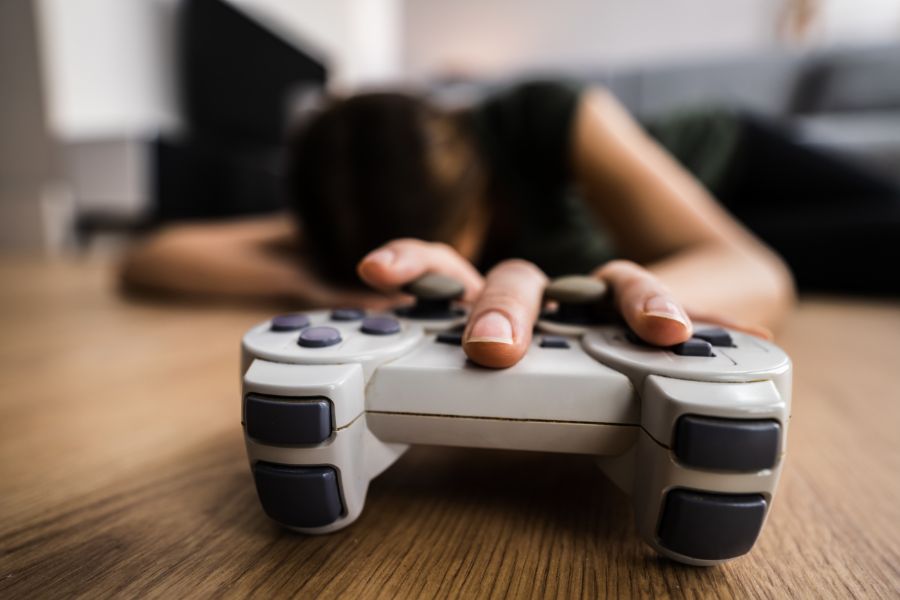 Mujer sosteniendo un mando de videojuego, simbolizando una adicción al juego ligada a una identificación inconsciente con un antepasado excluido del sistema familiar.