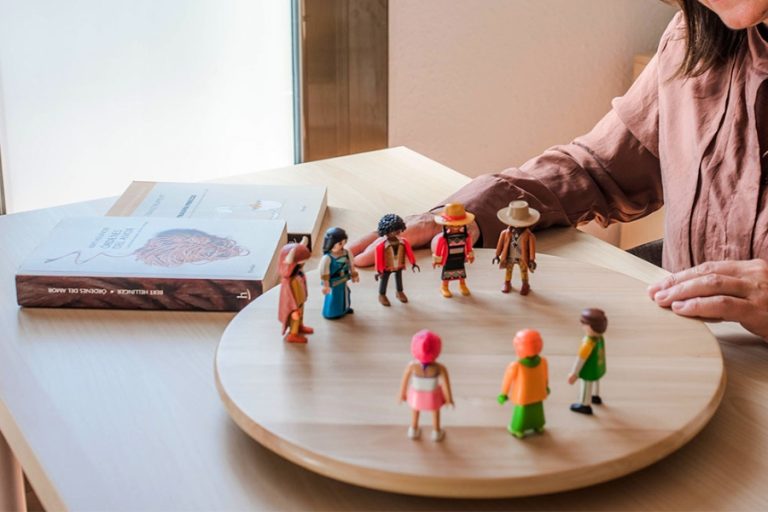 Mesa con figuras representando una constelación familiar, reflejando controversias sobre su consideración como pseudoterapia.