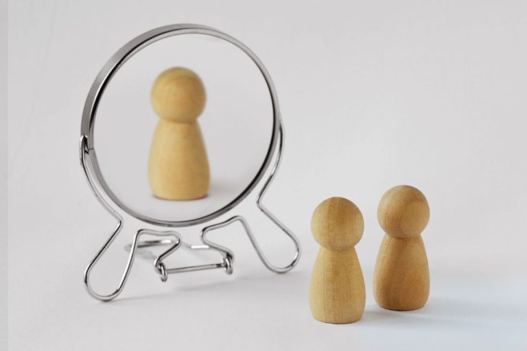 Representación simbólica del perfil de una persona narcisista: dos figuras están frente a un espejo, pero solo una se refleja.