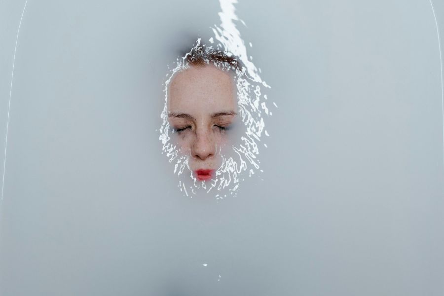 Rostro de mujer semisumergido en agua blanca, representando el aislamiento emocional y la confusión interna provocados por el gaslighting.