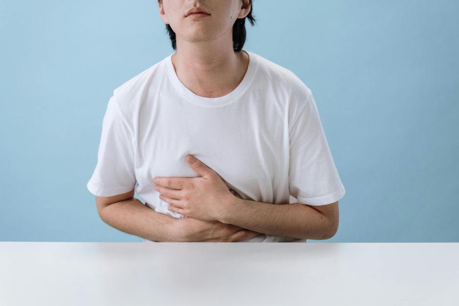 Hombre con dolor estomacal sujetando su abdomen, síntoma común asociado al SIBO o sobrecrecimiento bacteriano intestinal.