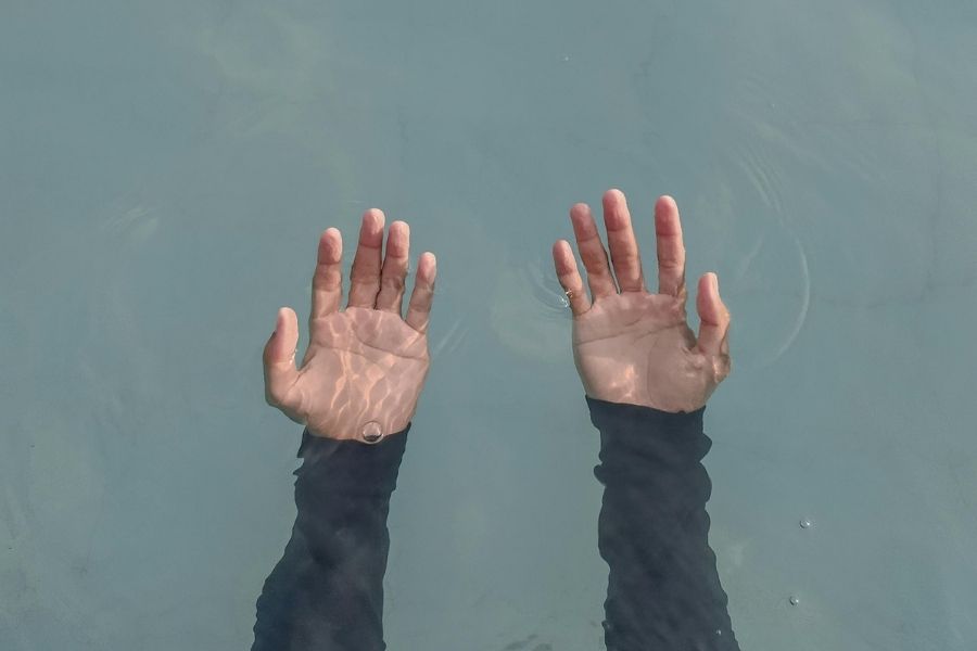 Manos bajo el agua representando debilidad muscular causada por el síndrome de Guillain-Barré