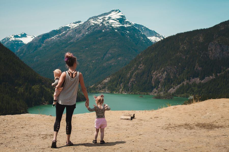 Madre con dos hijos contemplando un lago y montañas nevadas como representación del proyecto y sentido en familia. 