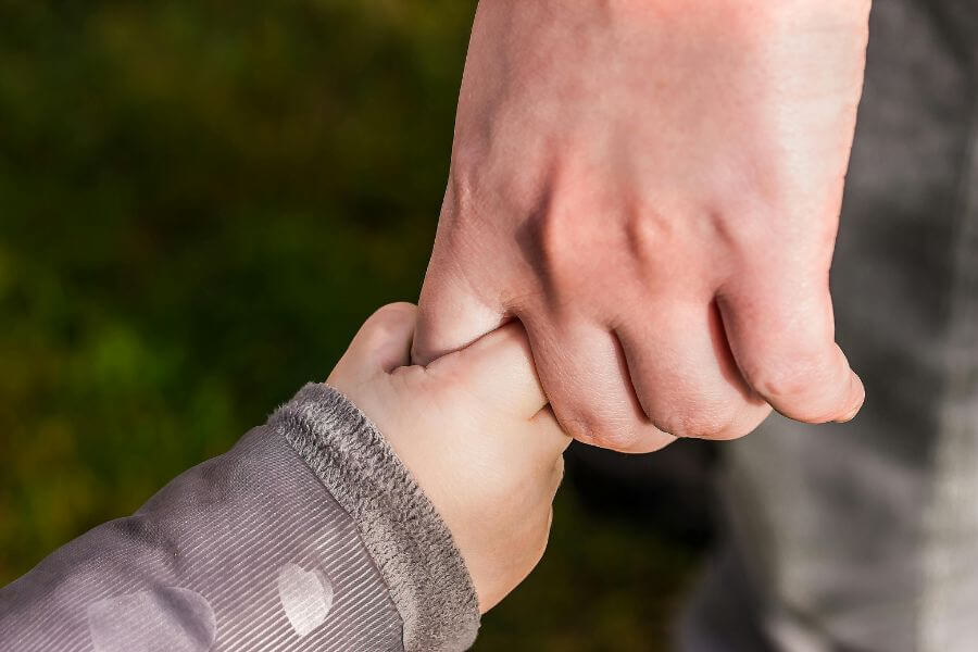 Mano de un adulto tomando la mano de un niño, simbolizando apoyo, seguridad y sanación emocional después del trauma infantil