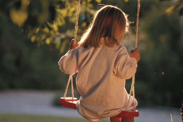 Niña pequeña en un columpio al atardecer, simbolizando vulnerabilidad y la importancia de prevenir el abuso infantil.