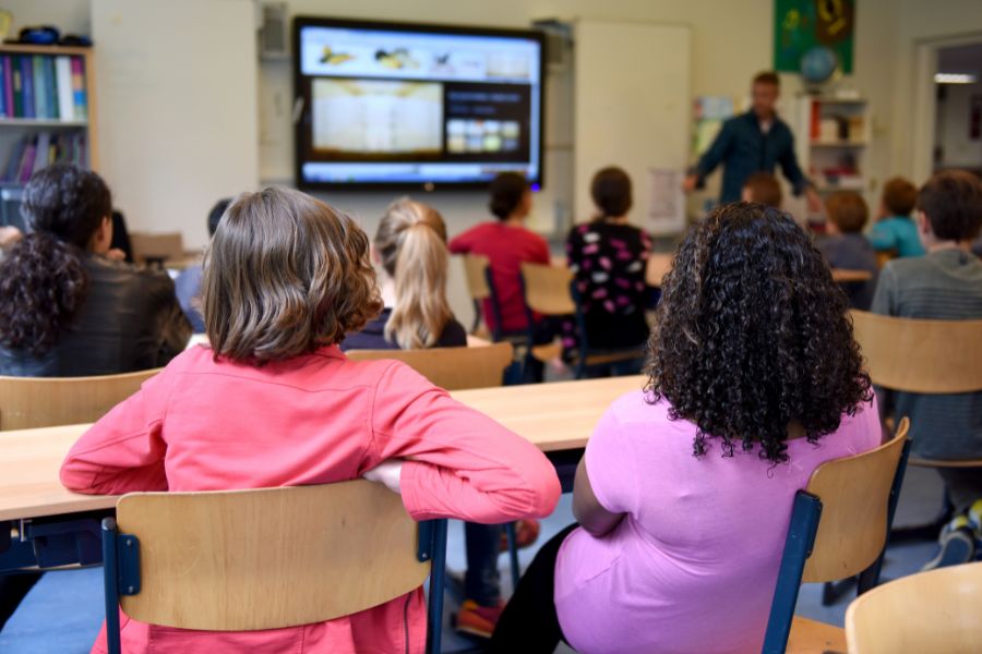 Niños en un aula escolar observando al docente, destacando la importancia de detectar y prevenir el abuso infantil en entornos educativos.