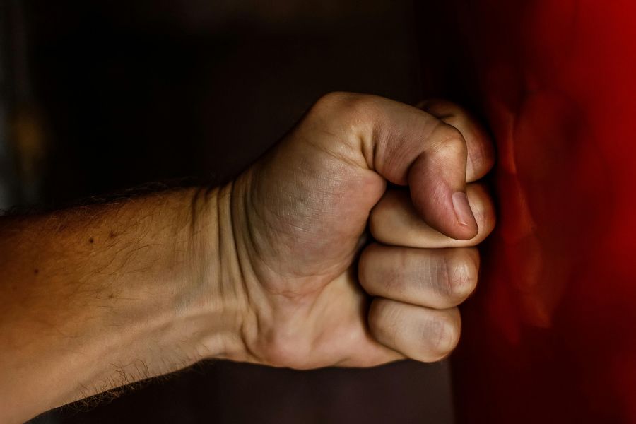 Puño cerrado golpeando una superficie como símbolo de agresión y violencia de género.