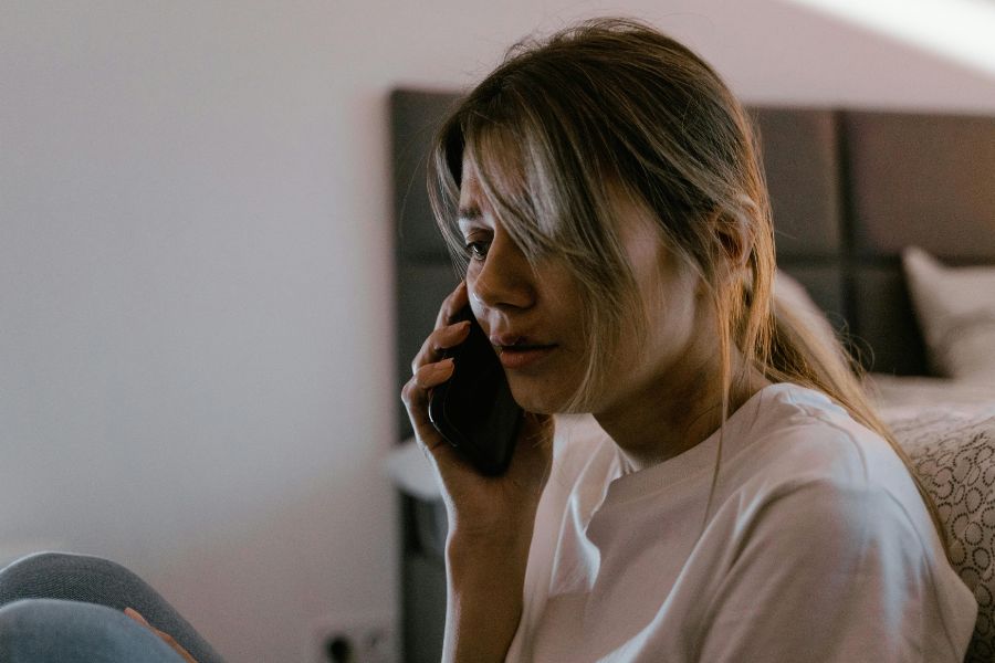 Mujer preocupada hablando por teléfono mientras pide ayuda en una situación de violencia de género.