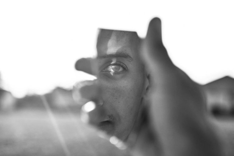 Rostro reflejado en un espejo fragmentado, simbolizando la baja autoestima y una autoimagen distorsionada.