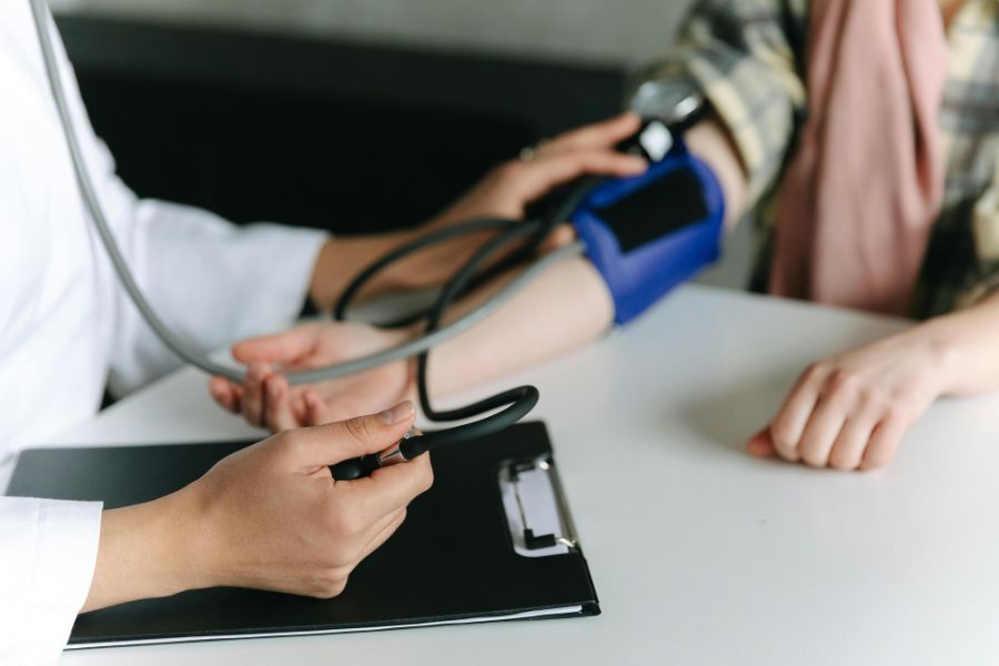 Profesional de la salud midiendo la presión arterial de un paciente para prevenir enfermedades cardiovasculares en Navidad.