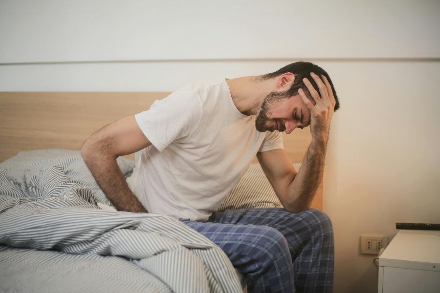 Hombre con dolor de cabeza y fatiga, mostrando síntomas relacionados con el estrés y enfermedades comunes en Navidad.