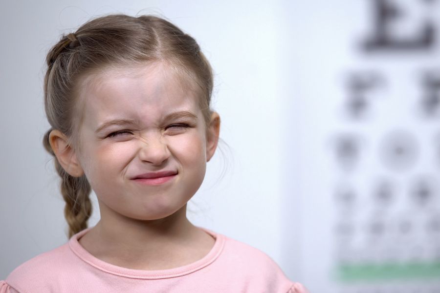 Niña entrecerrando los ojos, mostrando un síntoma típico de la miopía infantil