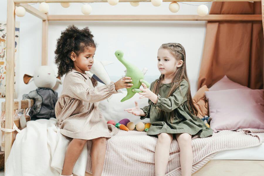 Dos niñas jugando y compartiendo un juguete, representando la inocencia, el juego y la expresión de la niña interior.