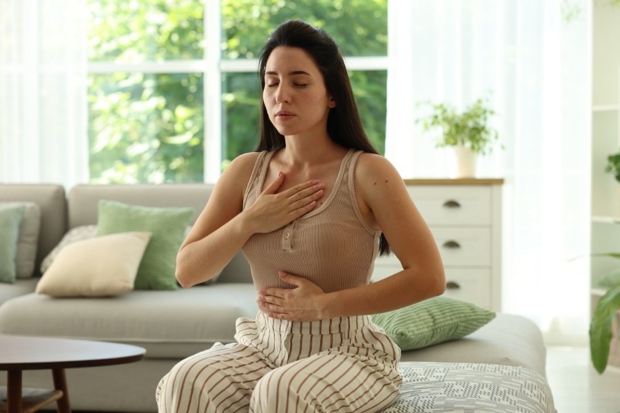 Mujer con las manos en el pecho y abdomen en un estado de calma y conexión corporal. Representa la liberación del sistema nervioso tras identificar la experiencia raíz de la fagofobia a través de la Descodificación Biológica.