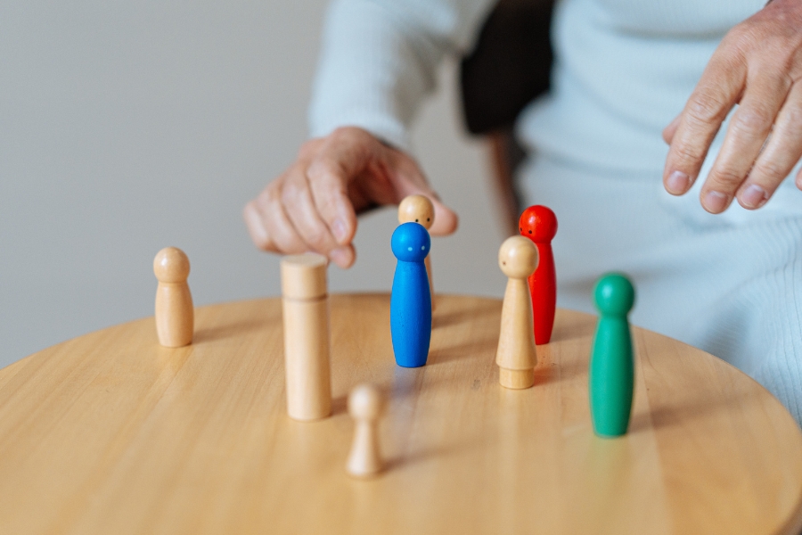 Manos colocando figuras sobre una mesa, representando una constelación familiar con diferentes representantes y una mirada sistémica