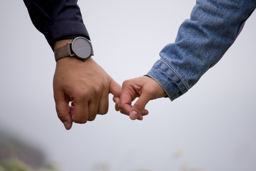 Primer plano de dos personas entrelazando sus dedos meñiques, simbolizando la fragilidad de la confianza, el miedo al vínculo y la resistencia al compromiso emocional.
