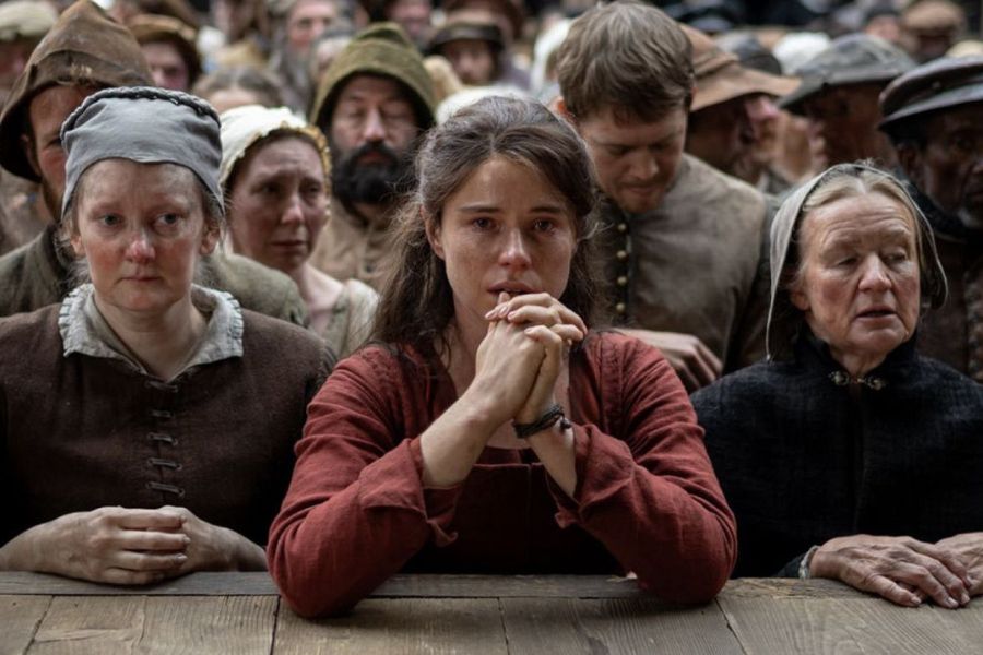 Escena de la película Hamnet: Agnes, con las manos entrelazadas, rodeada de una multitud con expresión de angustia