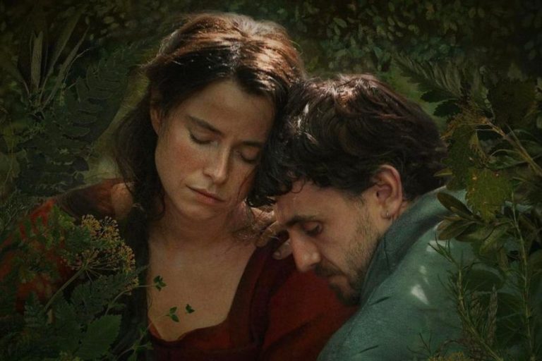 Imagen de la película Hamnet: Agnes y Will con los ojos cerrados, apoyados el uno en el otro, rodeados de vegetación