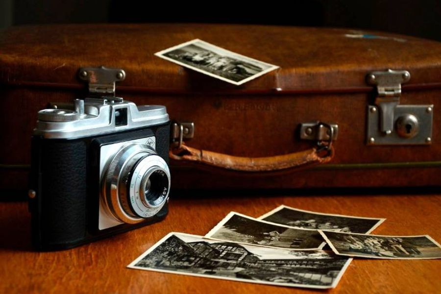 Cámara fotográfica antigua junto a fotografías en blanco y negro y una maleta de cuero, símbolo de la herencia y los vínculos transgeneracionales